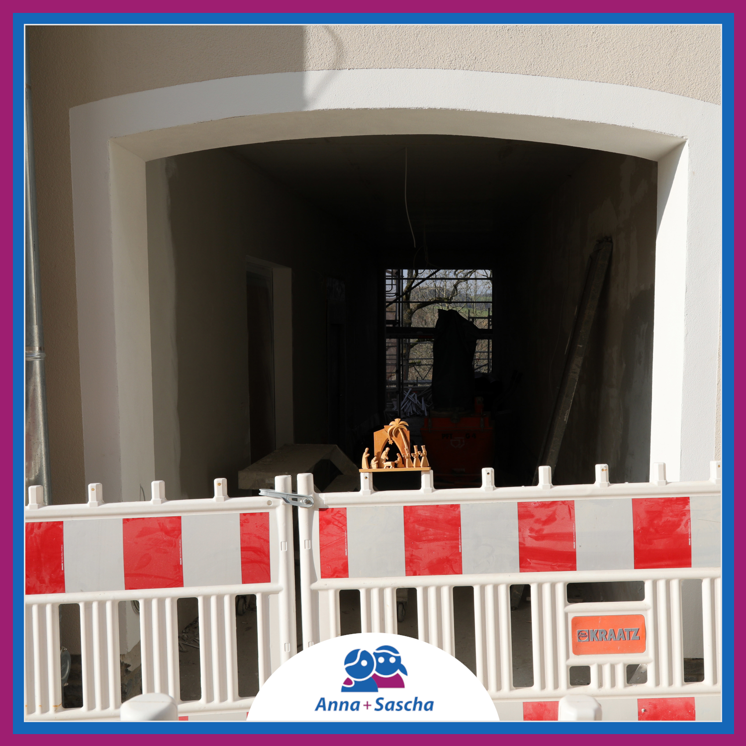 Wie ein Tunnel führt ein Gang von der Straße weg durch das Gebäude. Auf der rechten Seite ist die Wand zum Nachbarhaus. Auf der linken Seite ist die Eingangstür in unser Café. Am Ende des Durchgangs wird es heller und dort stehen Gerüste. Vor dem Durchgang stehen Absperrungen.